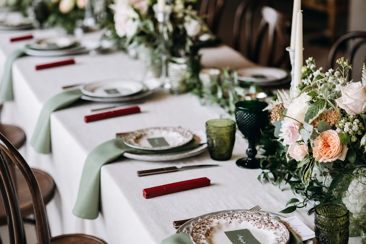Une table de mariage avec des éventails rouges fermés à côté des assiettes